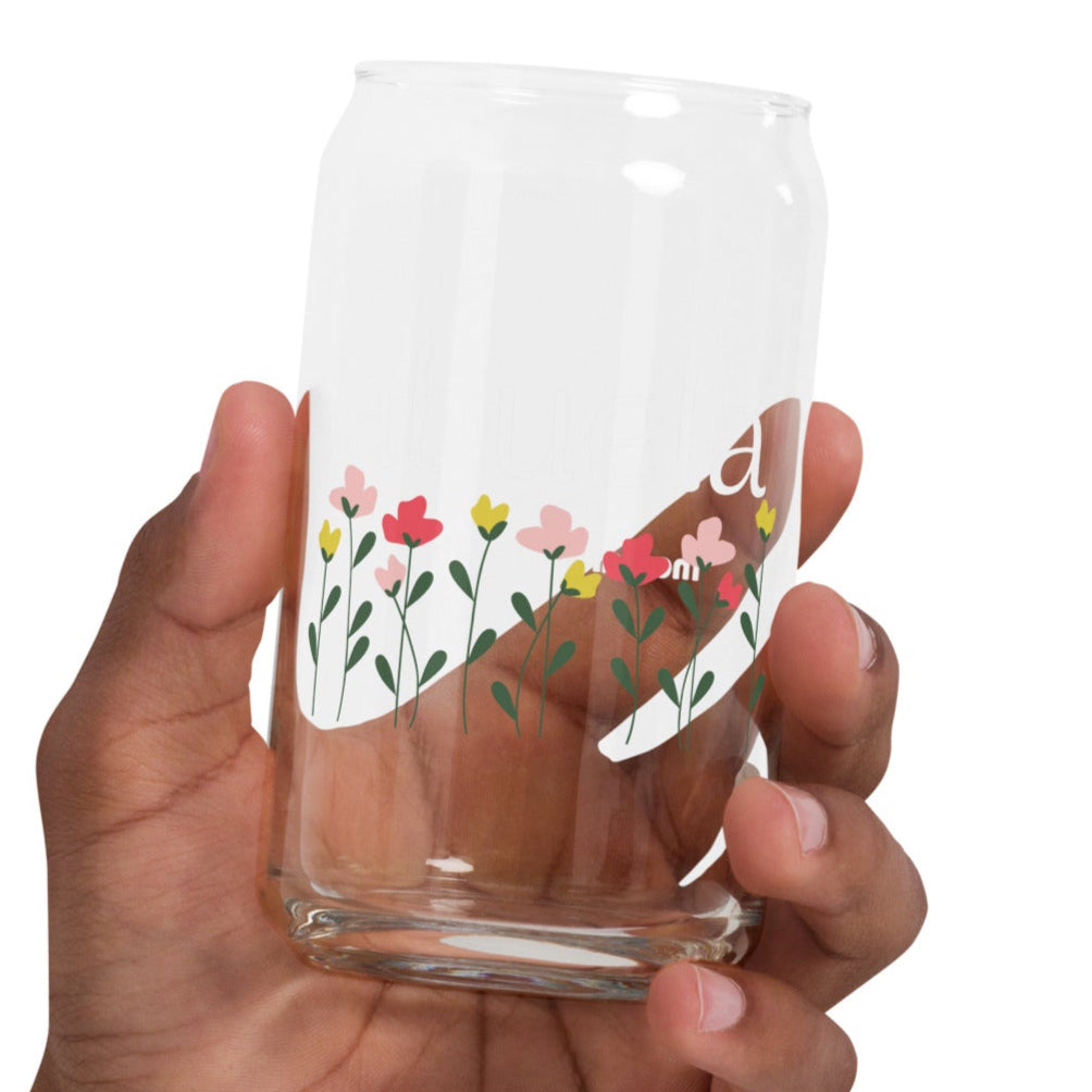 Clear glass with floral design held by a hand on a white background