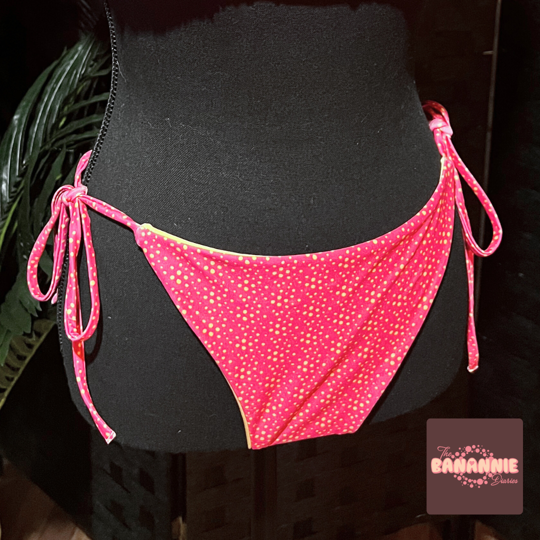 A pink bikini bottom with yellow dots and tie-side strings displayed on a mannequin. The brand logo 'The BANANINE Diaries' is visible in the image.
