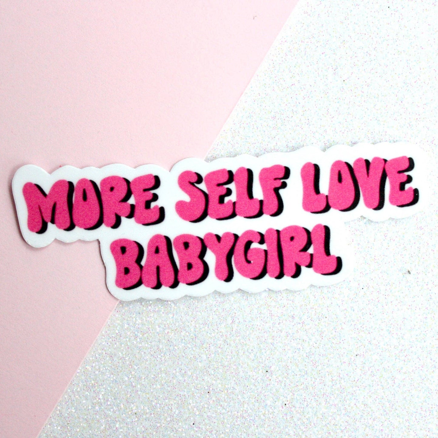 A vibrant pink waterproof sticker with the text 'MORE SELF LOVE BABY GIRL' printed on it.