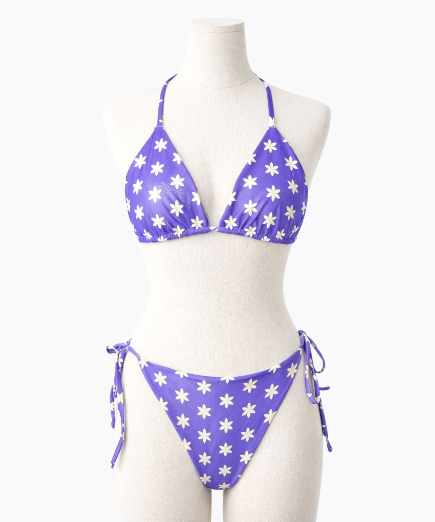 Purple bikini with light yellow floral pattern on a mannequin against a white background