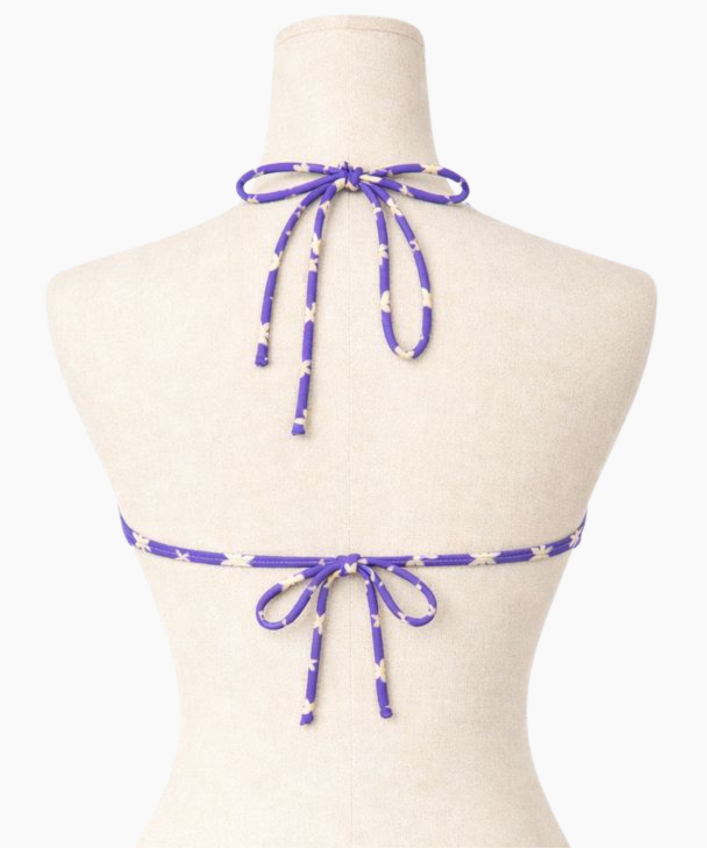 Back of purple bikini top with a light yellow floral pattern on a mannequin against a white background