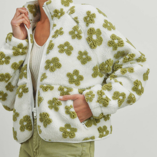 A woman wearing a white and green floral patterned jacket with long sleeves.