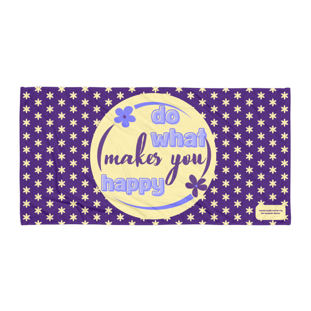 A purple towel with a yellow circle featuring the text 'DO WHAT MAKES YOU HAPPY' and decorated with a stars design.