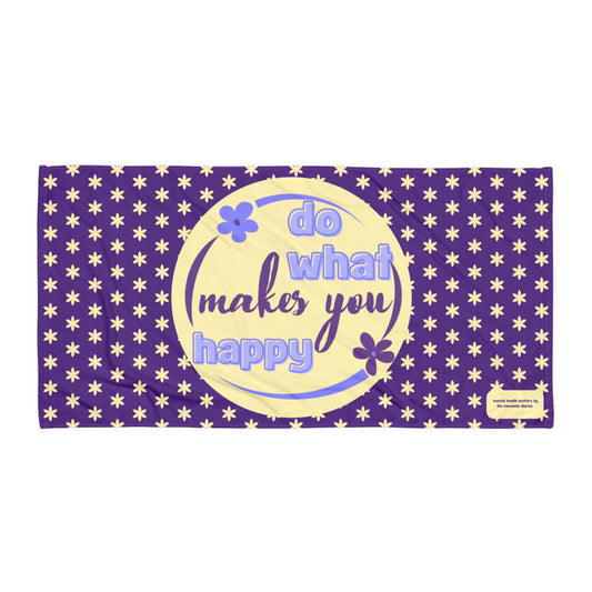 A purple towel with a yellow circle featuring the text 'DO WHAT MAKES YOU HAPPY' and decorated with a stars design.