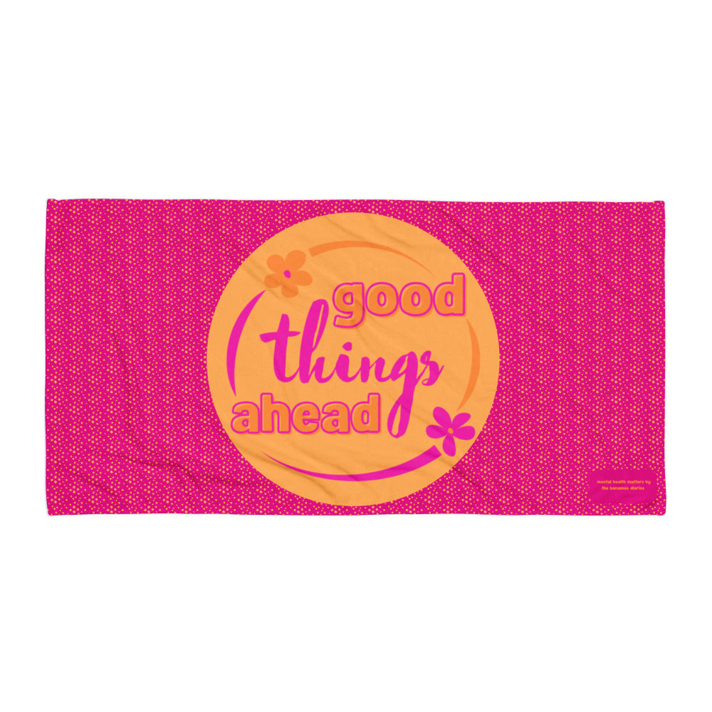 A vibrant pink beach/bath towel with an orange circle and the text 'Good Things Ahead' in the center, along with a polka dot design.
