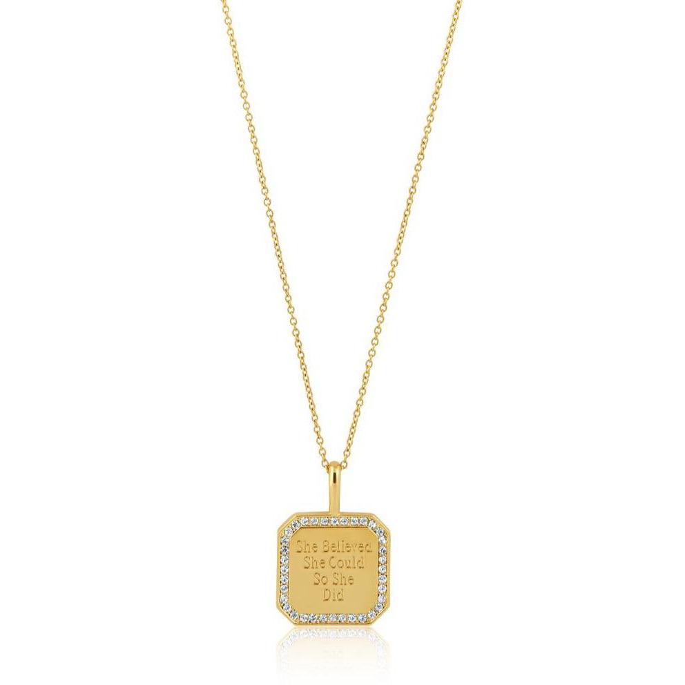A gold square pendant necklace with a faux pavé diamond border and engraved text reading 'She Believed She Could So She Did', shown on a white background with a subtle reflection.
