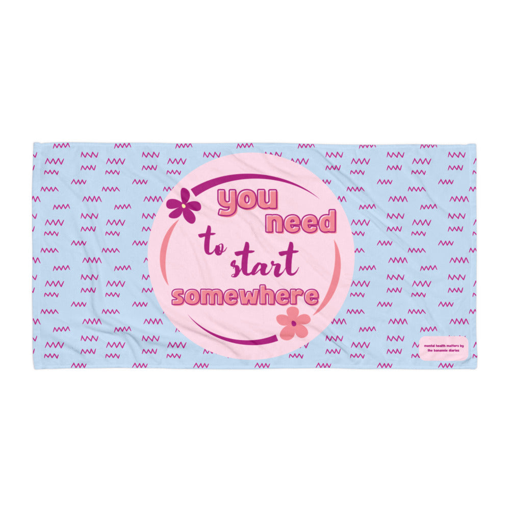 A plush blue and pink towel with the text 'You Need to Start Somewhere' and a zig zag pattern.