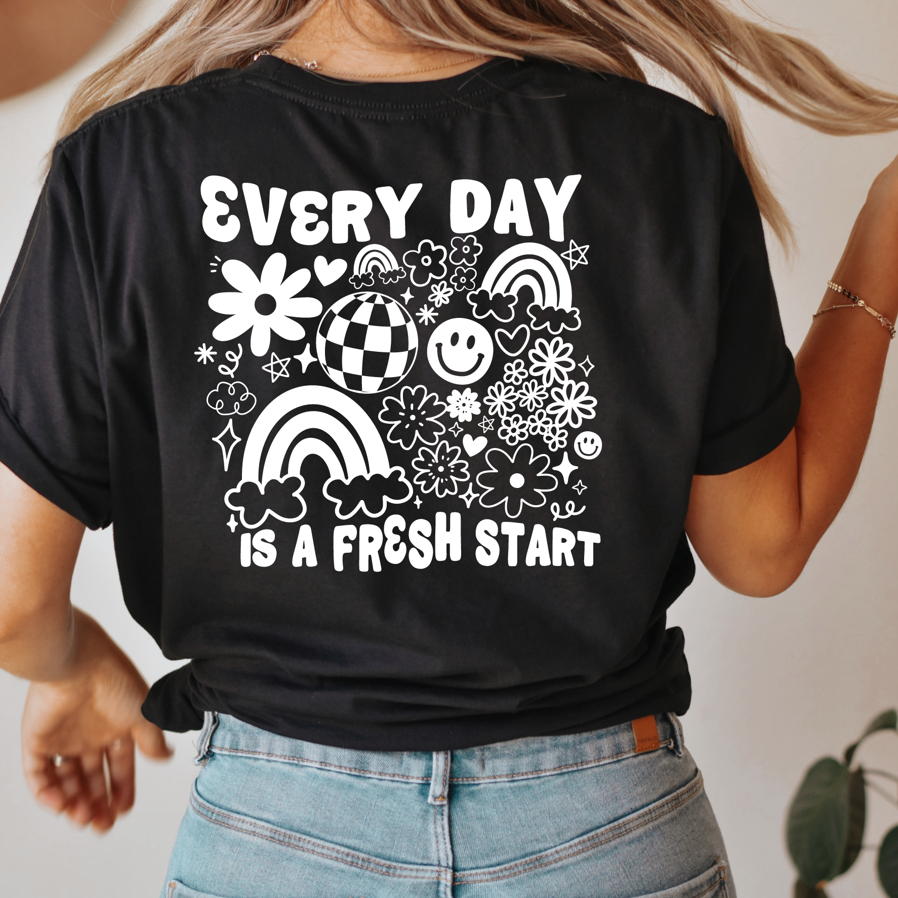 Person wearing a black t-shirt with white graphics and text, standing against a neutral background.