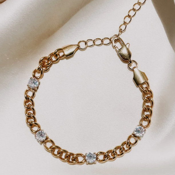 A gold-plated stainless steel bracelet with cubic zirconia accents, displayed on a white background.